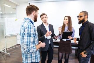 Head of department standing and talking to smiling young employees in office.jpeg