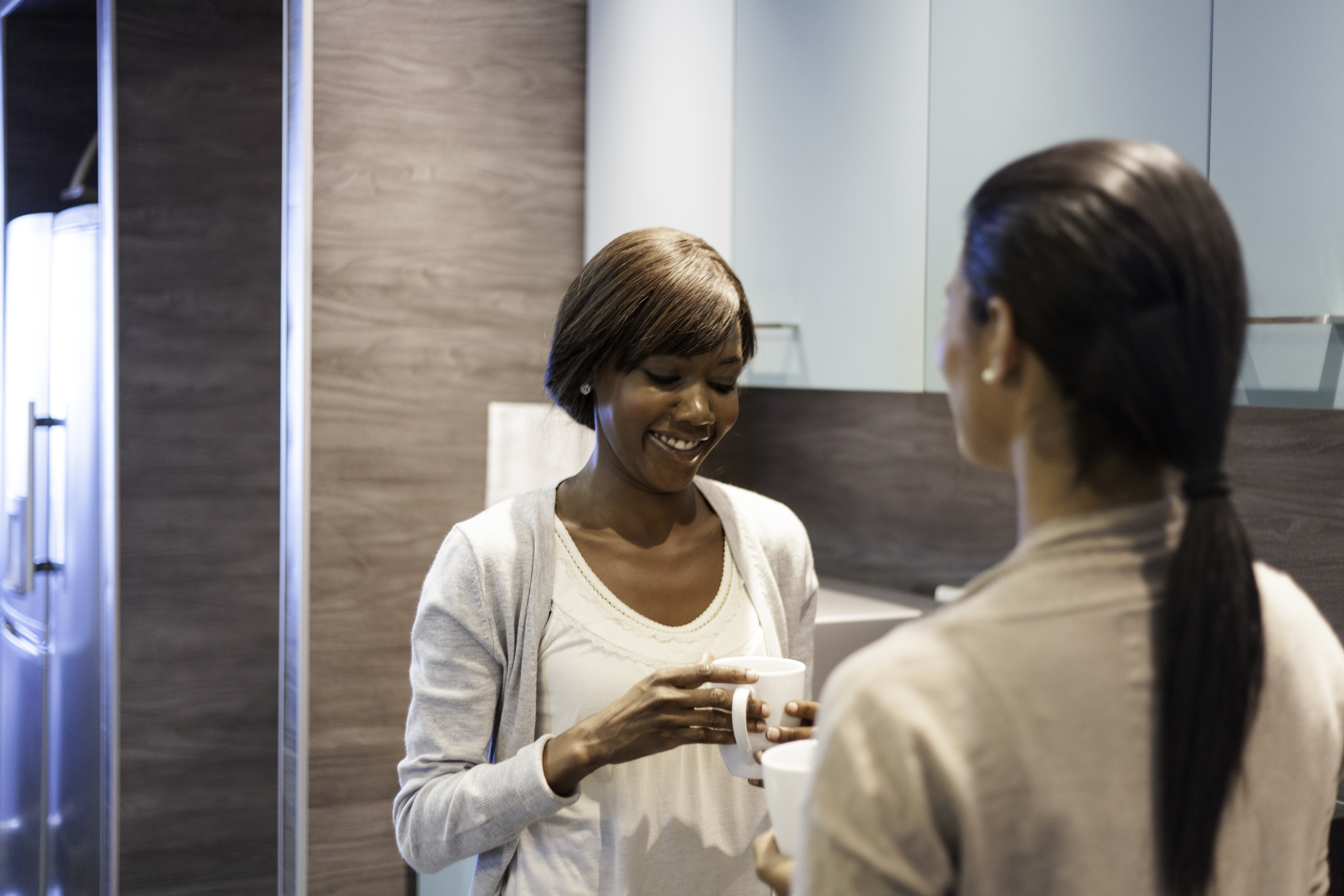 Female coworkers talking with coffee in hand