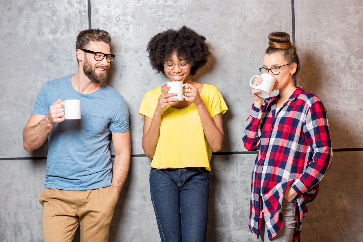 Three young workers talking over coffee